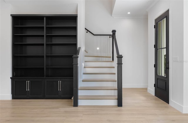 staircase featuring ornamental molding and hardwood / wood-style floors