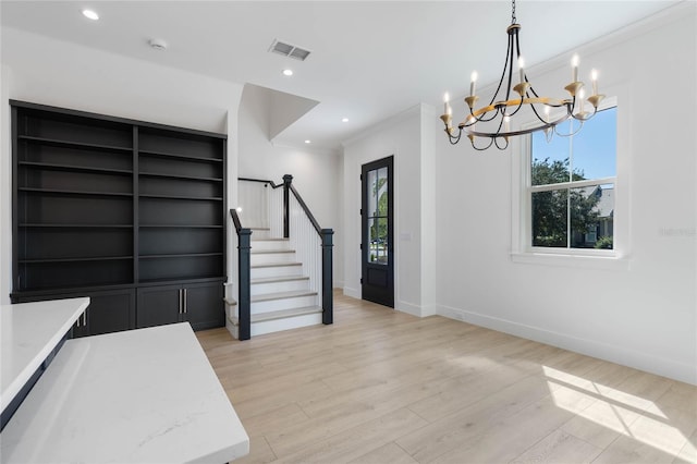 foyer entrance featuring light hardwood / wood-style flooring, plenty of natural light, an inviting chandelier, and crown molding