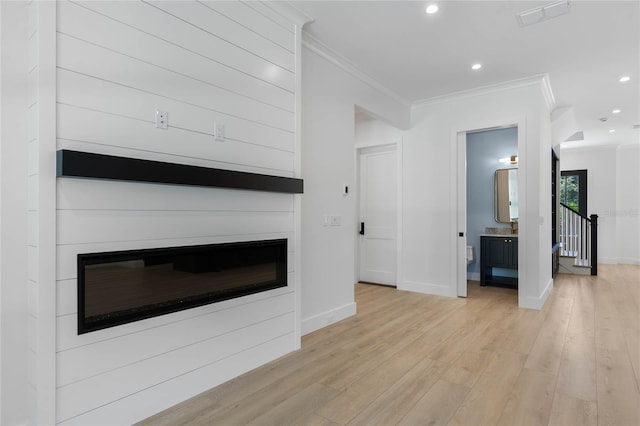 unfurnished living room with a large fireplace, light hardwood / wood-style flooring, and crown molding