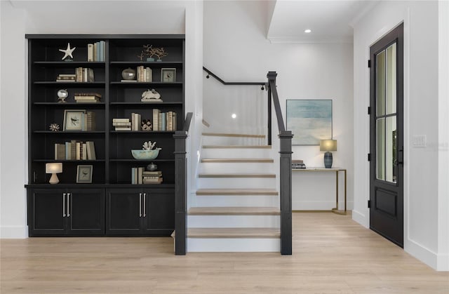 staircase with wood-type flooring and crown molding