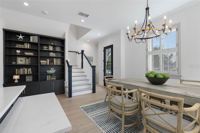 dining room with a notable chandelier, crown molding, and light hardwood / wood-style floors