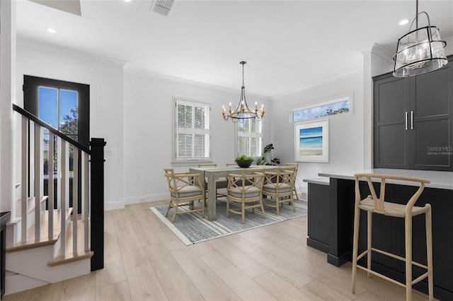 dining area with crown molding, a chandelier, and light hardwood / wood-style flooring