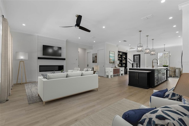 living room featuring crown molding, sink, light hardwood / wood-style flooring, and ceiling fan