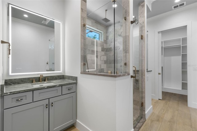 bathroom with hardwood / wood-style flooring, a shower with shower door, and vanity