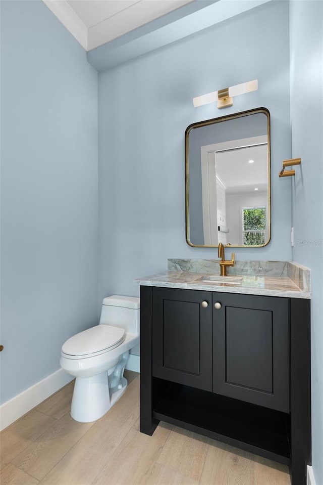 bathroom with hardwood / wood-style flooring, toilet, vanity, and ornamental molding