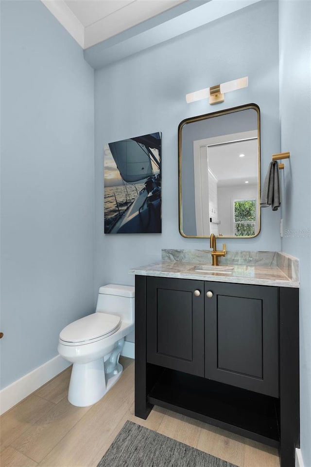 bathroom featuring wood-type flooring, toilet, vanity, and crown molding