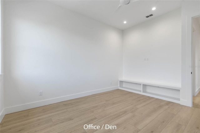 empty room featuring built in shelves and light hardwood / wood-style flooring