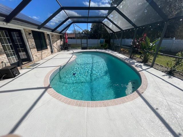 view of swimming pool featuring a patio and glass enclosure