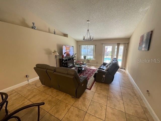 living room with french doors, a textured ceiling, an inviting chandelier, and light tile patterned floors