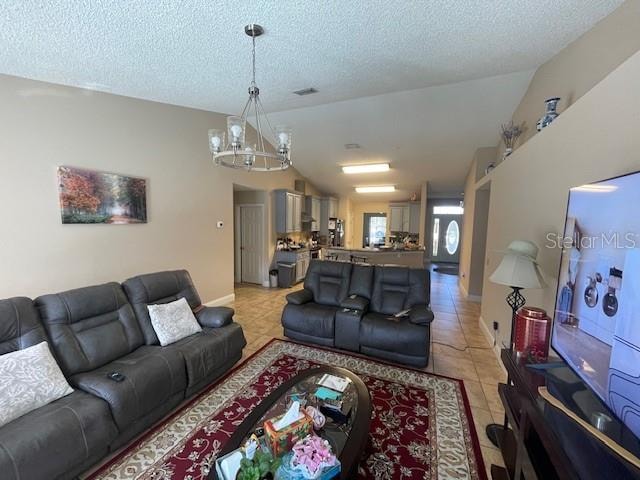 living room featuring vaulted ceiling, a textured ceiling, an inviting chandelier, and light tile patterned floors