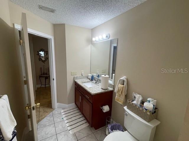 bathroom featuring vanity, a textured ceiling, toilet, and tile patterned flooring