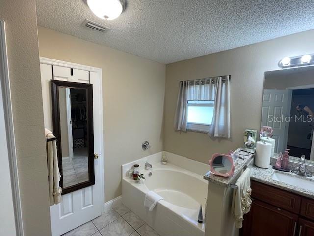 bathroom with vanity, a textured ceiling, a tub to relax in, and tile patterned flooring