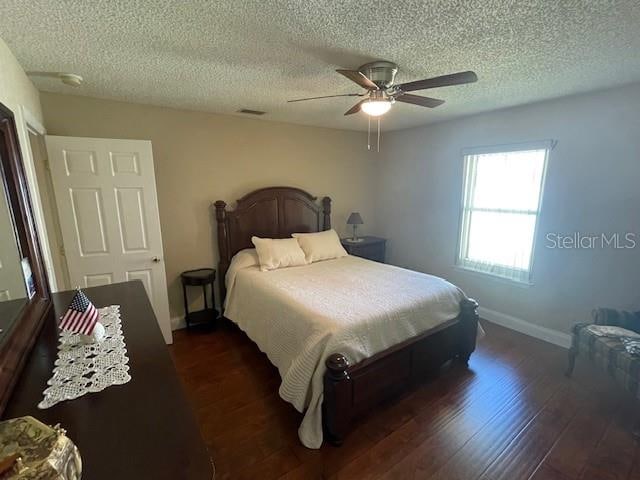 bedroom featuring a textured ceiling, dark wood-type flooring, and ceiling fan