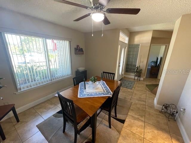 tiled dining area with ceiling fan, a textured ceiling, and plenty of natural light