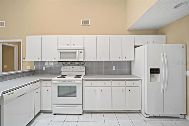 kitchen with white cabinetry, tasteful backsplash, light tile patterned floors, and white appliances