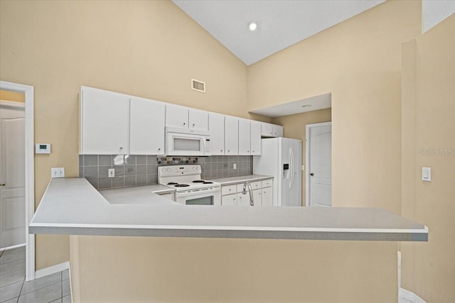 kitchen with kitchen peninsula, tasteful backsplash, white cabinetry, light tile patterned flooring, and white appliances