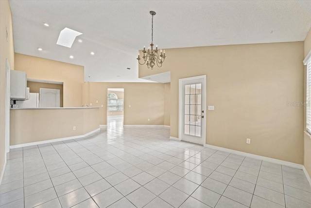 tiled spare room with high vaulted ceiling, a notable chandelier, a textured ceiling, and a skylight