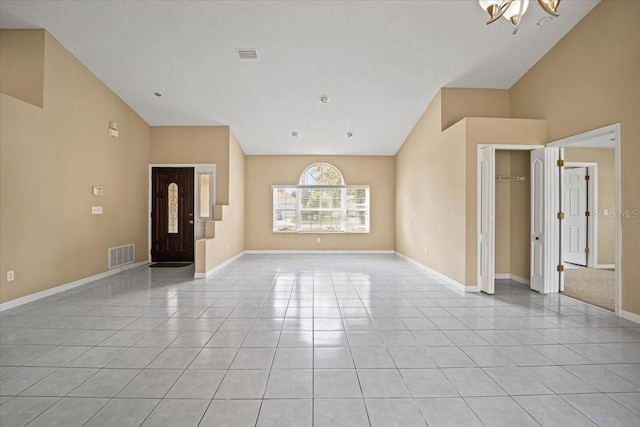 unfurnished living room with a chandelier, a textured ceiling, high vaulted ceiling, and light tile patterned floors