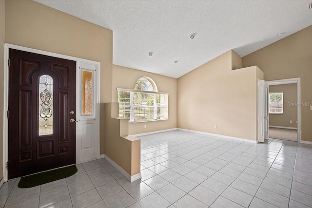 entrance foyer featuring light tile patterned flooring, a textured ceiling, and lofted ceiling