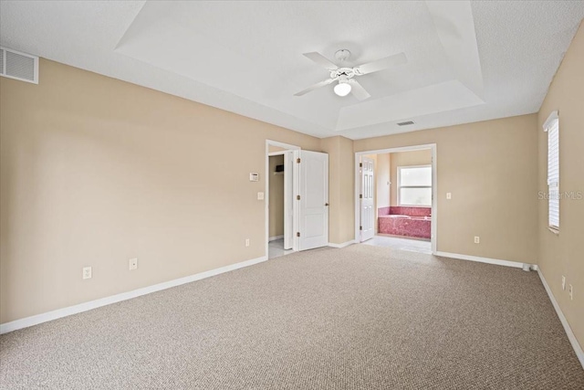 unfurnished room featuring carpet floors, a textured ceiling, a tray ceiling, and ceiling fan