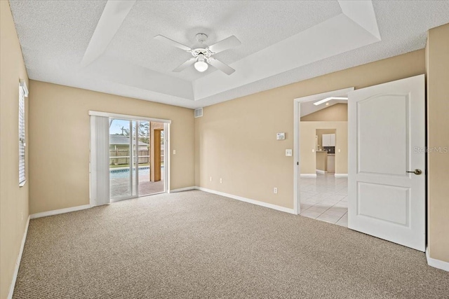 carpeted empty room featuring a textured ceiling, a raised ceiling, and ceiling fan