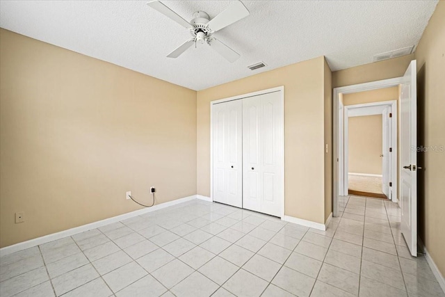 unfurnished bedroom with a closet, a textured ceiling, light tile patterned floors, and ceiling fan