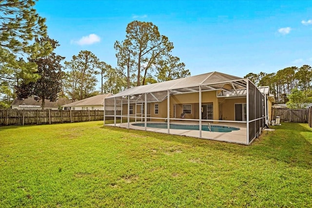 rear view of house featuring glass enclosure, a fenced in pool, and a lawn