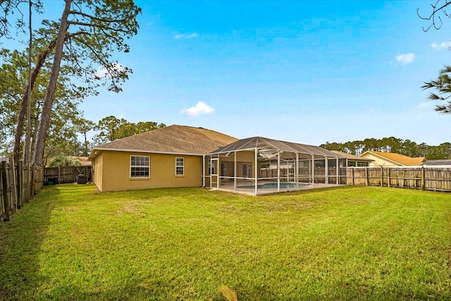 rear view of house featuring a lawn and glass enclosure