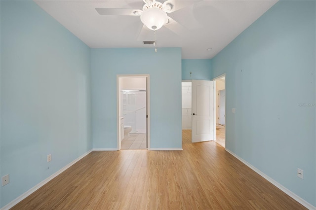 unfurnished bedroom featuring a closet, light hardwood / wood-style floors, a walk in closet, and ceiling fan