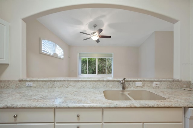 kitchen featuring white cabinetry, sink, light stone counters, and ceiling fan