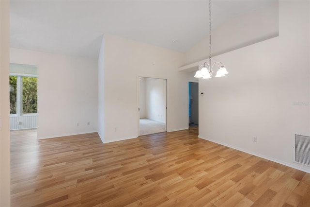 empty room with light hardwood / wood-style flooring, high vaulted ceiling, and an inviting chandelier