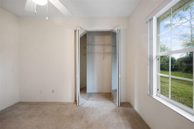 unfurnished bedroom with light colored carpet, a closet, and ceiling fan