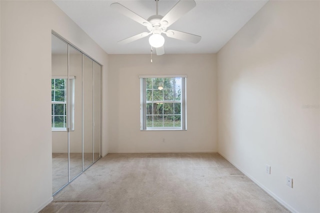 unfurnished bedroom featuring light colored carpet, a closet, and ceiling fan