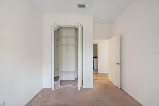 unfurnished bedroom featuring a closet and light colored carpet