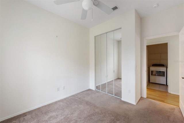 unfurnished bedroom with a closet, ceiling fan, washer / clothes dryer, and light colored carpet