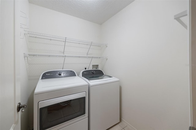 laundry area featuring independent washer and dryer, a textured ceiling, and light tile patterned floors