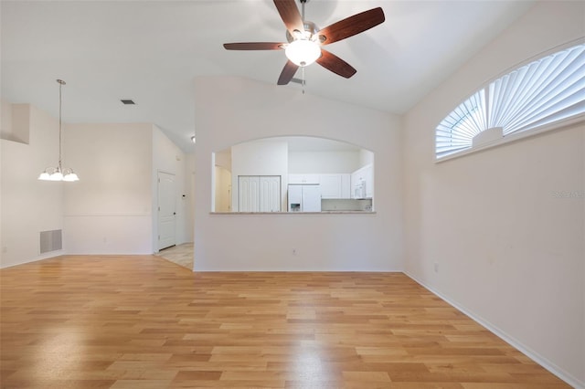 unfurnished living room featuring lofted ceiling, ceiling fan with notable chandelier, and light hardwood / wood-style floors