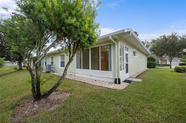 view of side of property with a sunroom, central AC, and a lawn