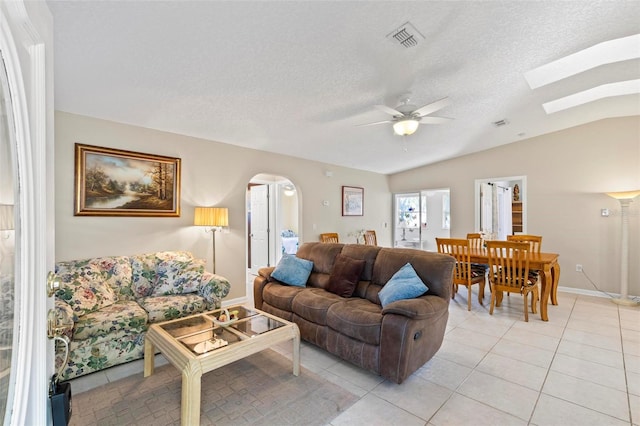 tiled living room with ceiling fan, a textured ceiling, and lofted ceiling