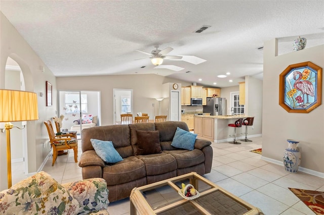 tiled living room featuring lofted ceiling, a textured ceiling, and ceiling fan