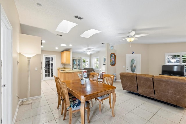 tiled dining space with sink, ceiling fan, a skylight, and plenty of natural light