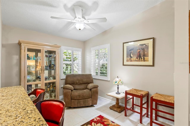 living area with a textured ceiling, light tile patterned flooring, vaulted ceiling, and ceiling fan