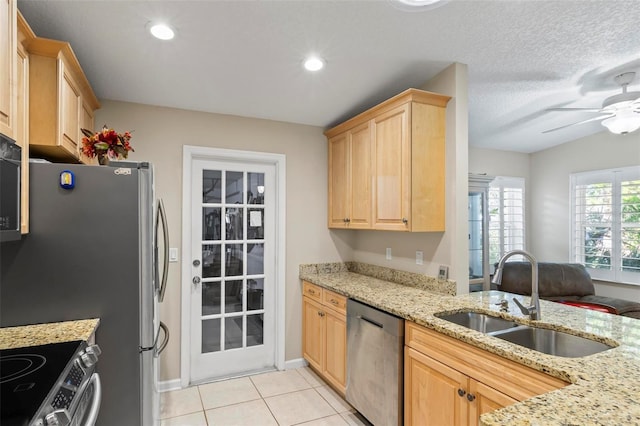 kitchen featuring sink, light tile patterned floors, light brown cabinetry, appliances with stainless steel finishes, and light stone counters