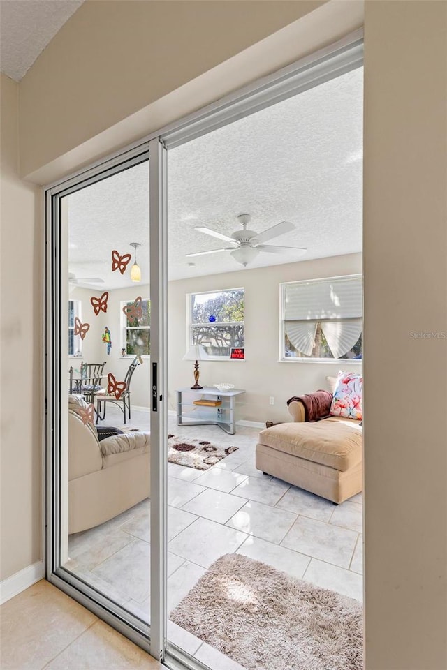 entryway featuring a textured ceiling, ceiling fan, and light tile patterned floors