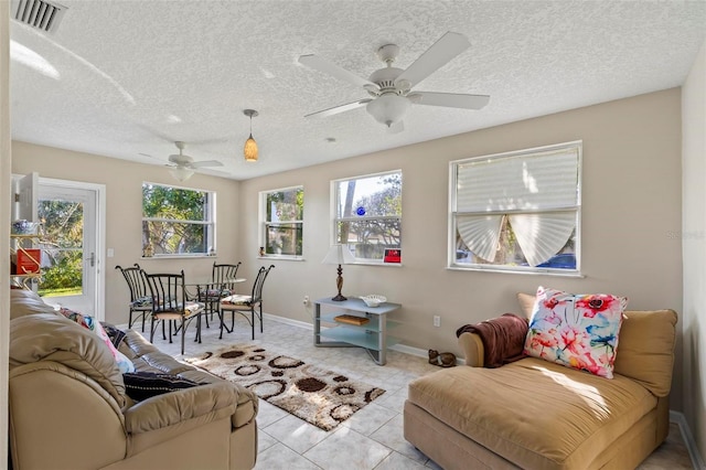 living room with a textured ceiling, light tile patterned floors, and ceiling fan