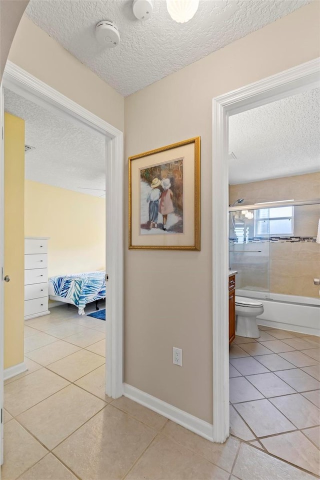 hall with a textured ceiling and light tile patterned flooring