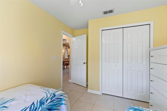 bedroom with a closet, a textured ceiling, ceiling fan, and light tile patterned floors