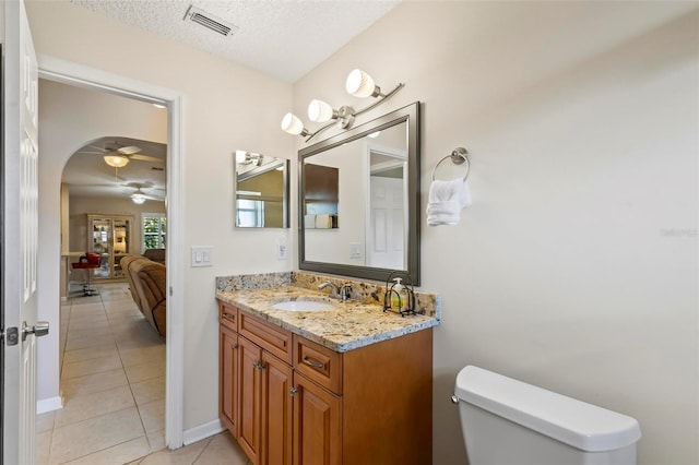 bathroom featuring tile patterned floors, toilet, vanity, a textured ceiling, and ceiling fan