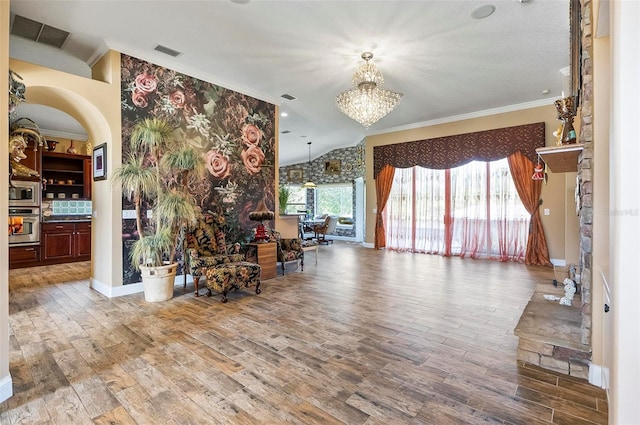 unfurnished living room with ornamental molding, a chandelier, wood-type flooring, and a healthy amount of sunlight