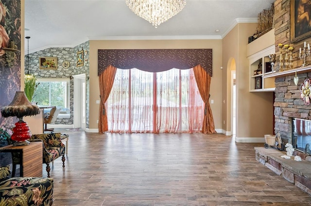 living room with lofted ceiling, an inviting chandelier, wood-type flooring, ornamental molding, and a fireplace